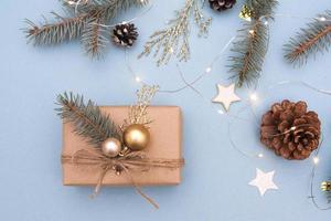 regalo de navidad con decoración. concepto foto regalo de navidad, preparación de año nuevo. abeto y ramitas doradas, adornos, guirnaldas sobre un fondo azul.