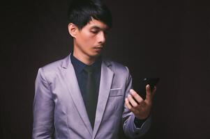 Asian man in suit looking at his phone photo