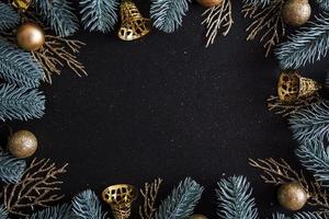 Top view Merry Christmas black background decorated with Happy New Year Christmas tree branches and baubles with copy space. Winter holiday card decoration festive fun concept, flat lay. photo