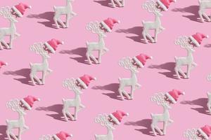 Pattern with a glamorous reindeers in a Santa hat on a pink background photo
