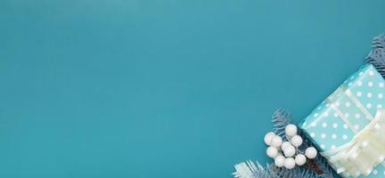 Banner with flat lay Christmas gift, berries and pine turquoise background with copy space photo