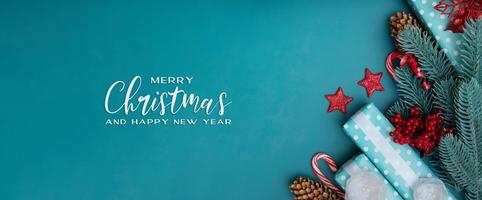 Banner de felicitación de feliz navidad con decoraciones de vacaciones de invierno laicas planas sobre fondo turquesa foto