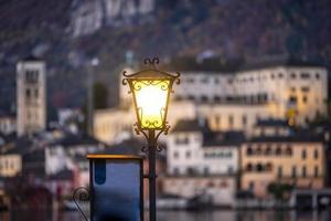 An old-style public lamp of Orta village, on the shore of the same name lake, Piedmont Region, Northern Italy. In the background the San Giulio island, home of a cloistered nuns convent, UNESCO Site
