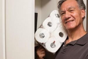 Man Putting away a Package of Toilet Paper in the Closet photo