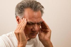 Senior Man in pain with Headache rubbing his temples for relief photo