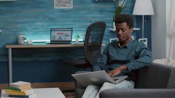 African american man browsing using laptop computer, searching social media video
