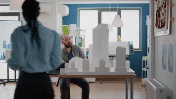 Compañeros de trabajo mirando la tableta y el modelo de construcción para inspirarse en un proyecto urbano. video