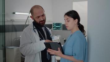 médico e enfermeira com tablet falando sobre tratamento para o paciente video