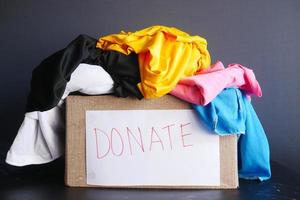 caja de donación con ropa de donación en una mesa de madera. foto