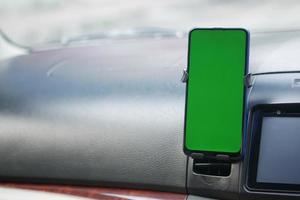 teléfono inteligente con pantalla verde en el salpicadero del coche foto