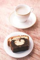 Rebanada de pastel de chocolate de panadería y té en la mesa foto