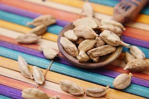 Cerca de cardamomo en una cuchara en la mesa foto