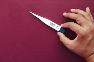 close up of man hand holding digital thermometer. photo