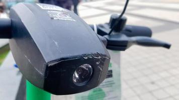 Close up of the steering wheel of an electric scooter with a flashlight. City electric scooter rental outside. Riding safety problem. Ecological transport concept. photo