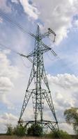 One tower, high voltage power lines. High voltage cables. High voltage electrical tower on the field. against the blue sky. Vertical photography.