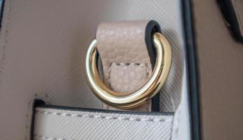 Metal gold loop oval ring attached to a leather bag. Selective focus. Part for a secure connection between two objects. Sewing accessories in the form of a ring for sewing bags, glossy. photo