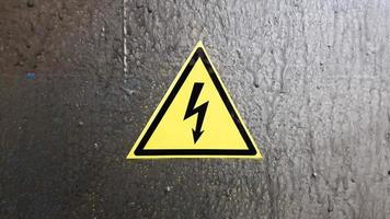 señal de seguridad amarillo y negro sobre un fondo de metal plateado. relámpago de alto voltaje en un triángulo precaución precaución peligro electricidad muerte. foto