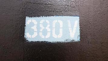 380 vatios pintado sobre tapa metálica gris de cuadro eléctrico de alta tensión. foto