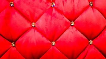 back of a red sofa. Red fabric texture background, Chesterfield style decoration with buttons, retro fabric. Retro diamond-shaped soft style fabric decorate with buttons. red velvet background photo