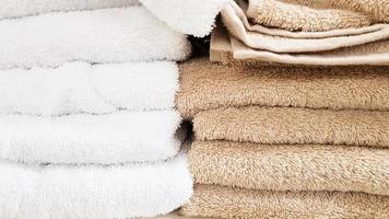 pilas de toallas de baño mullidas de varios colores en el escaparate de una tienda. toallas de felpa de algodón en una pila en los estantes de un supermercado. foto