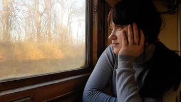 mujer bonita joven que viaja en un tren clásico sentado cerca de la ventana. filtro vintage. niña turista mira por la ventana de un viejo tren en movimiento, disfrutando de viajes y hermosos paisajes naturales foto