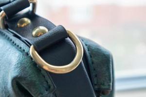 Metal gold loop oval ring attached to a leather bag. Selective focus. Part for a secure connection between two objects. Sewing accessories in the form of a ring for sewing bags, glossy. photo