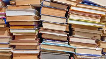 Many used old books in the school library. chaotic layout of stacks of literature, selective focus. A pile of books ends with stacked background. books in a library - backdrop photo