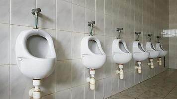 baños públicos con gran cantidad de urinarios de cerámica. baño público grande, cuencos de pared en el baño. Los urinarios preparan cuencos para hombres. foto