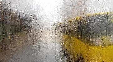 Rain on the rear window of a car in autumn. Inside view of the road with moving cars in the city through the window from the car with rain drops. driving a car in the field of view of the rear window. photo