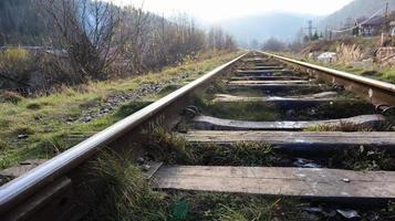 Close Up perspective view of railway tracks on a bright sunny day. Rails and wooden sleepers in oil with crushed stone. low down view of railway train transport metal steel rails. photo