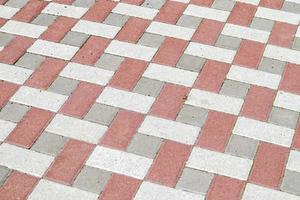 Concrete or paved newly laid gray and red paving slabs or stones for floors or walkways. Concrete paving slabs in the backyard or road paving. Garden brick path in the courtyard on a sandy foundation.