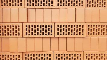 Red brick background with holes. Red perforated brick with rectangular holes. Rough texture of rows of red light bricks. View of the corrugated side and perforated upper surfaces of the clay brick. photo