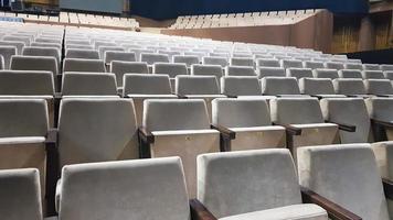 a lot of old beige upholstered chairs without people in the hall for performances and films. Background from many chairs in the stands in a concert hall or theater. photo