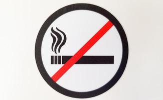Redondo rojo y negro, señal de prohibido fumar, pegatina en un lugar público sobre un fondo blanco.