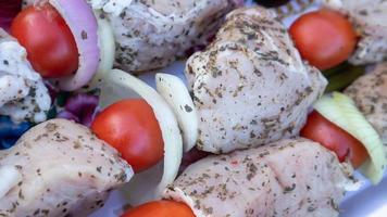 Raw pork shashlik with spices, cherry tomatoes and onions on skewers ready to cook. Fresh raw kebab. photo