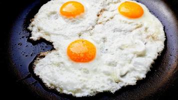 Tres huevos fritos de gallinas camperas en una sartén antiadherente caliente foto