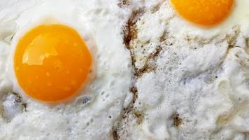 Close-up photo of two scrambled eggs in black frying pan