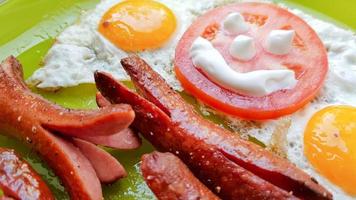 Top view of fried egg and sausages on a green plate, serving breakfast for the baby photo