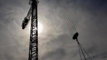 Construction crane on a background of blue sky. Close view of a construction crane. Abstract industrial background with a silhouette of a construction crane over the sky with clouds. photo