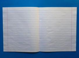 Cuaderno abierto sobre un forro blanco sobre una mesa de madera azul foto