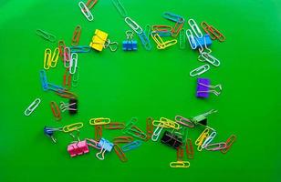 pile of paper clips isolated on green background, documents, office supplies concept, dirty office desk. Empty place for writing and text. Top view, layout. flat lay photo