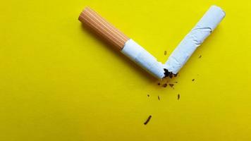 Broken cigarette isolated on a yellow background. View from above photo