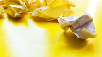 Ball crumpled paper ball isolated on a yellow background. Crumpled paper for texture. Crumpled paper after a brainstorming was thrown into the bin. A piece of yellow crumpled paper photo