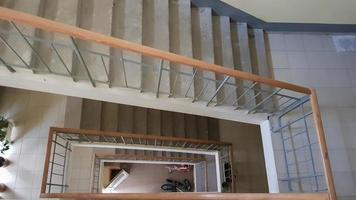 escalera moderna en edificio residencial. escalera en perspectiva. baldosas de cerámica gris. Escalera común con valla de madera marrón y escalones de concreto. vista desde arriba. foto