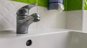 Old aluminum sink mixer. Water tap in the toilet for clean hands. photo