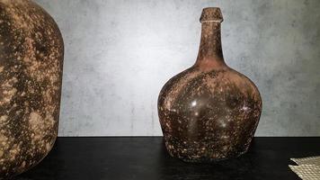 large vintage vases or jugs of colored glass as decoration elements in a modern interior near a gray concrete wall. Decoration of an apartment or house. photo