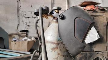 Messy old welding mask and equipment indoors with workshop background. photo