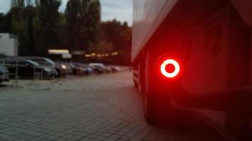 Close-up shot of the rear round red marker light of a truck. Rear light for a truck. The background is blurred. The concept of safe travel on the road at night. photo