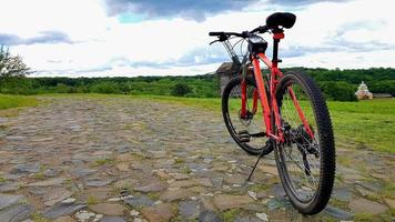 Ucrania, Kiev - 11 de junio de 2020. Hermosa imagen de paisaje natural de verano con una bicicleta de montaña roja se encuentra en una carretera rocosa. foto