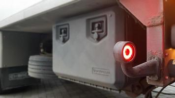 Close-up shot of the rear round red marker light of a truck. Rear light for a truck. The background is blurred. The concept of safe travel on the road at night. photo